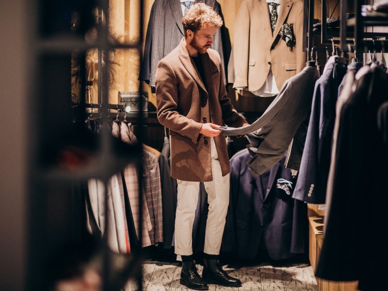 Young handsome man choosing cloth at shop